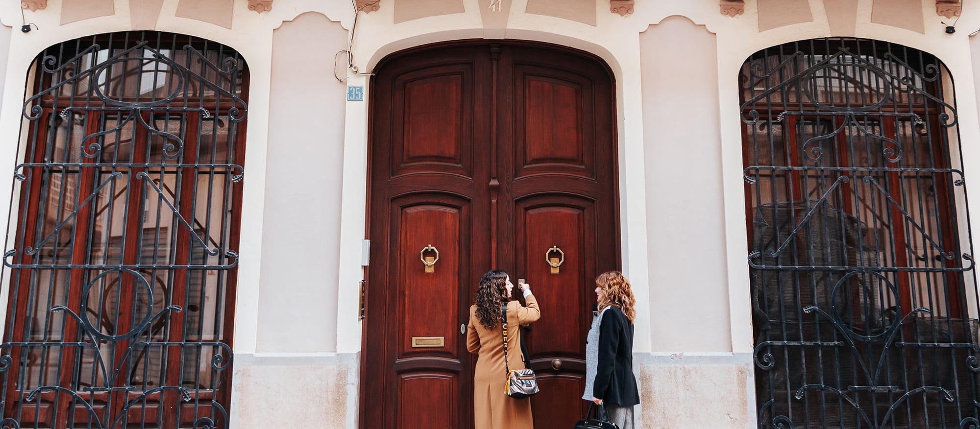 Dos mujeres frente a una puerta antigua.
